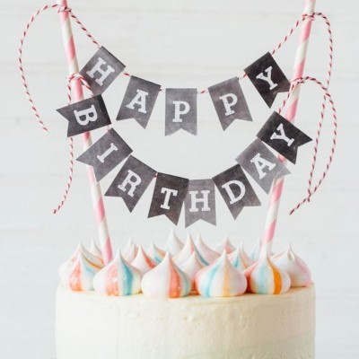 Bolo branco decorado com suspiros coloridos e bandeira HAPPY BIRTHDAY