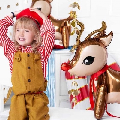 Criança com salopete castanha e balões de rena dourados