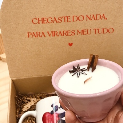 Vela branca em copo rosa com anis e canela, caixa de cartão com mensagem em vermelho e caneca com desenho de panda