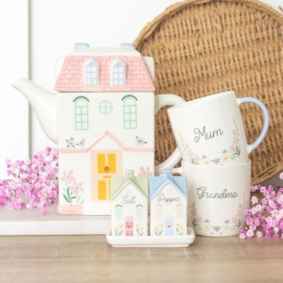 Conjunto cerâmico de bule e chávenas com saleiro e pimenteiro tematizados em forma de casas coloridas com decoração floral.