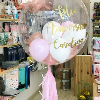 Balão transparente com balões rosa e branco e texto 'feliz Aniversário Carolina' numa loja