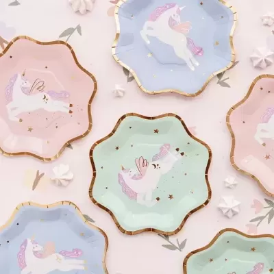 Pratos de papel coloridos com unicórnios e bordas douradas em fundo floral