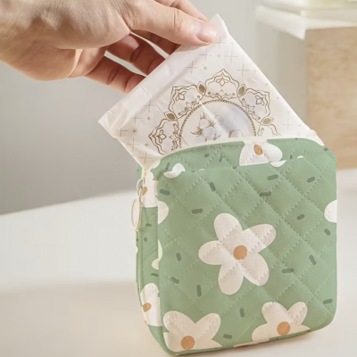 Necessaire verde com flores brancas sendo puxado pacote branco decorado por mão