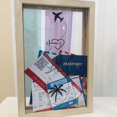 Caixa de vidro decorativa com bilhetes de avião, passaporte e desenho de avião e coração.