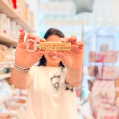 Abridor de garrafas com cabo em cortiça natural e metal prateado com gravação segurado por mulher em loja