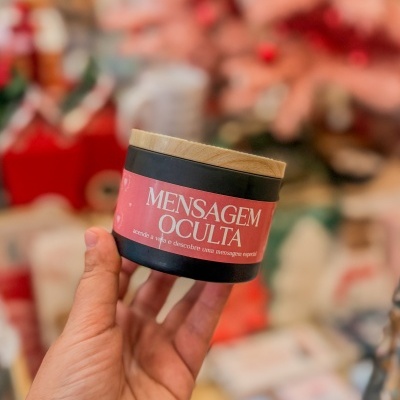 Recipiente preto com tampa de madeira e etiqueta cor-de-rosa com texto em português