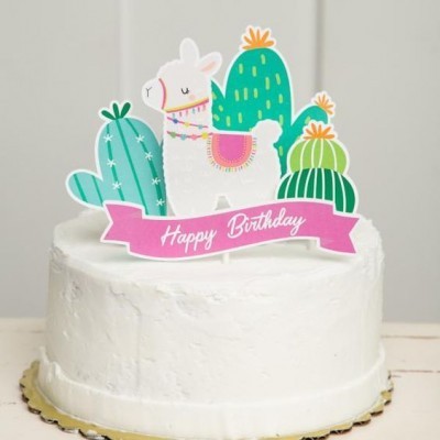 Bolo branco com enfeite de lhama e cactos e faixa rosa 'Happy Birthday' no topo