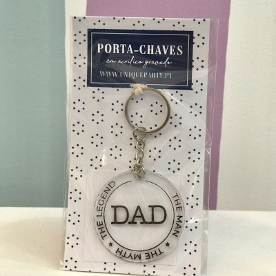 Porta-chaves redondo transparente com texto 'DAD' e embalagem com padrão de pontos pretos.