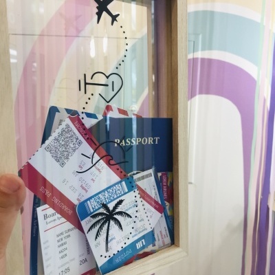 Quadro com passaporte azul e bilhetes de avião, no contexto de parede colorida em arco-íris