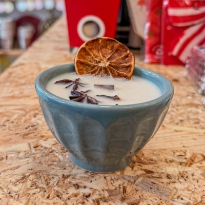 Taça azul com creme branco, laranja seca e anis-estrelado numa superfície de madeira