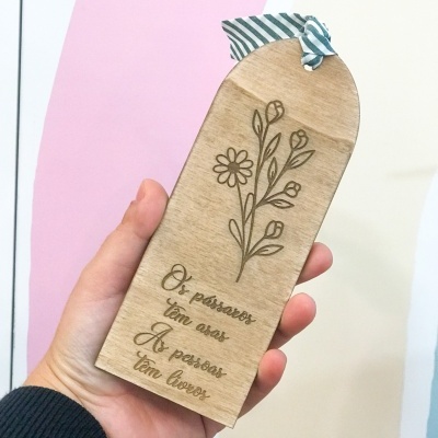 Marcador de livro em madeira clara com gravura floral e texto em português com fita decorativa azul e branca