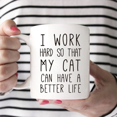 Caneca branca com texto em inglês segurada por pessoa com camisola às riscas