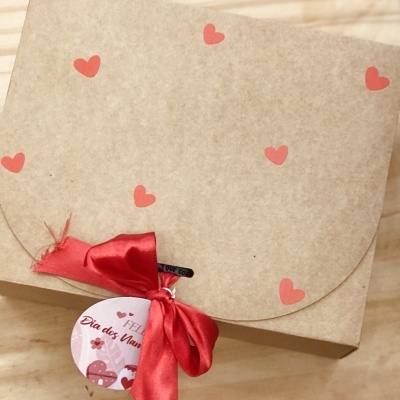 Caixa de papel castanho com corações vermelhos, fita vermelha e etiqueta de Dia dos Namorados