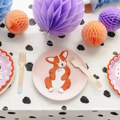 Pratos infantis de papel com desenhos de cães, talheres de madeira e decoração em papel colorida