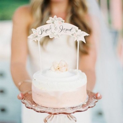 Bolo redondo branco e bege claro com topper Sarah & Jared numa base de vidro