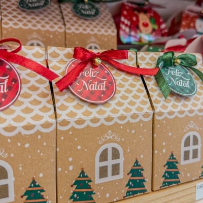 Caixas de presente de Natal de papel com fitas e etiquetas 'Feliz Natal', decoradas com árvores e padrão branco.