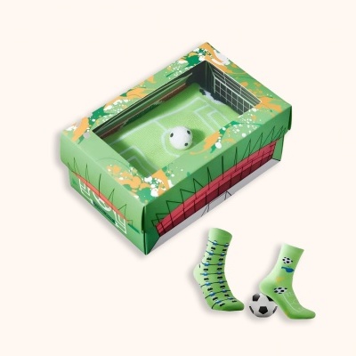 Caixa verde com design de campo de futebol, bola pequena e duas meias verdes com padrões variados