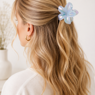 Presilha de cabelo floral iridescente azul no cabelo loiro ondulado de mulher com argola dourada