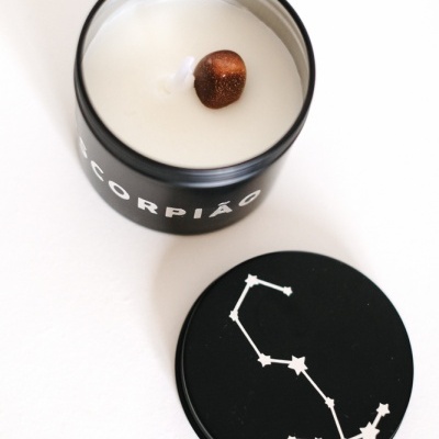 Vela em frasco preto decorada com texto Escorpião e constelação na tampa