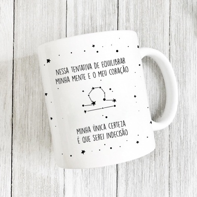 Caneca branca com texto em português e estrelas pretas sobre fundo de madeira clara