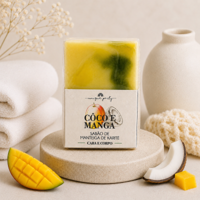 Sabão em barra amarelo e verde com rótulo branco e pedaços de manga e coco num ambiente claro e neutro