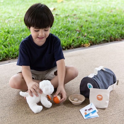 Criança a brincar com cão de pelúcia e acessórios de brinquedo ao ar livre