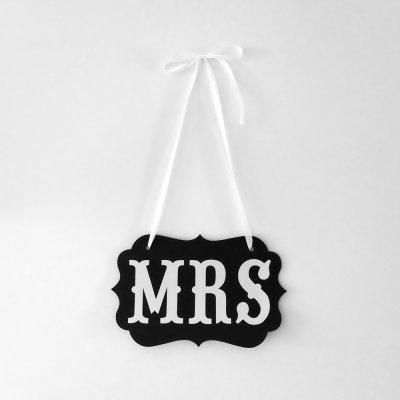 Placa decorativa preta com texto MRS em branco pendurada por fita branca