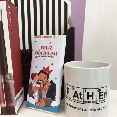 Caneca branca com elementos da tabela periódica e barra de chocolate com ilustração familiar
