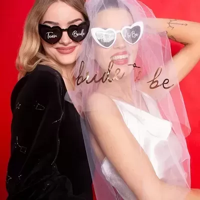 Duas mulheres com óculos em forma de coração e véu com texto bride to be