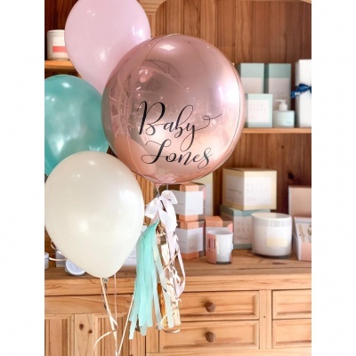 Balões coloridos com texto Baby Jones em frente a armário de madeira com caixas de cosméticos