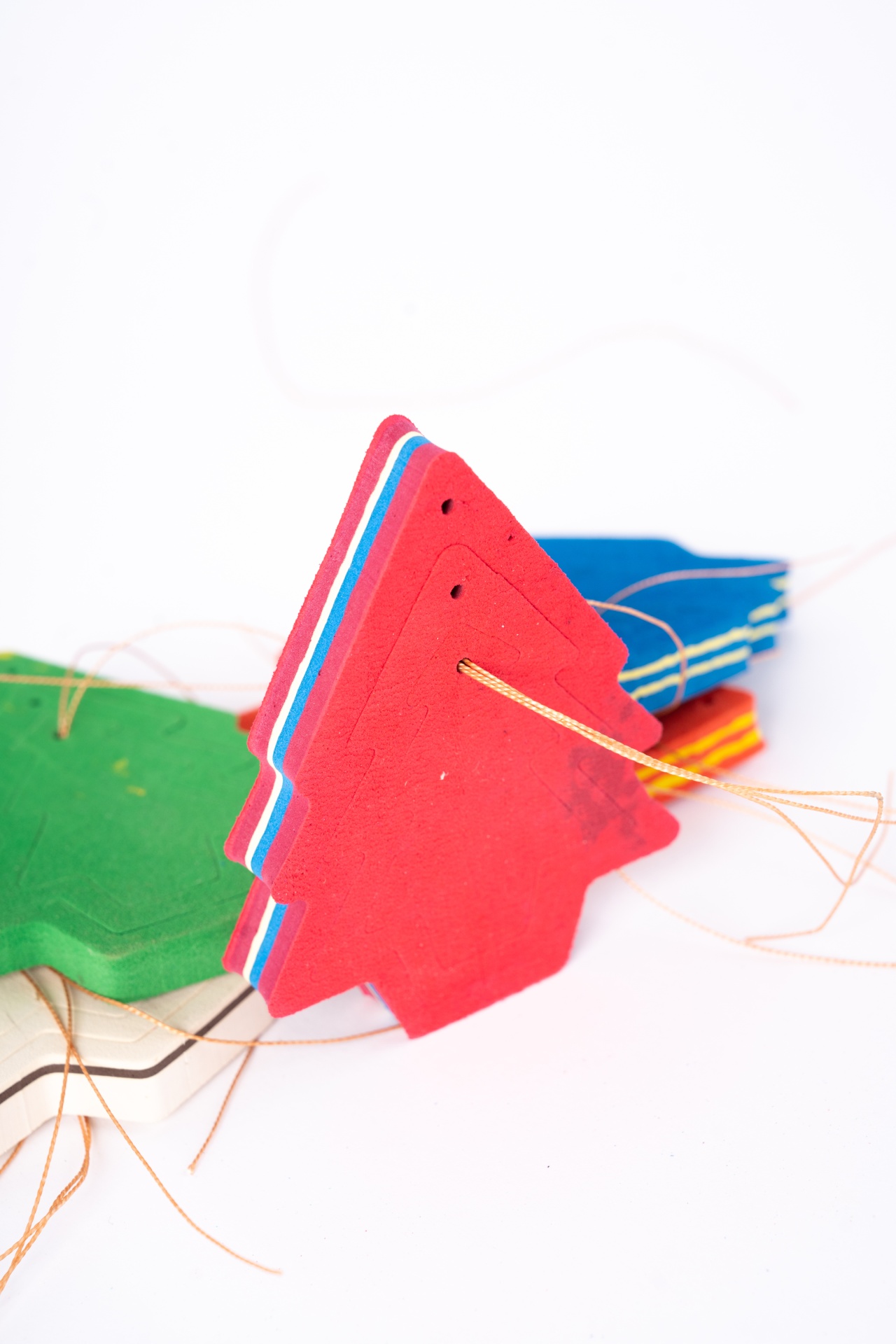 Pendentes de Natal Cartões coloridos em forma de árvore de natal com fios finos num fundo branco