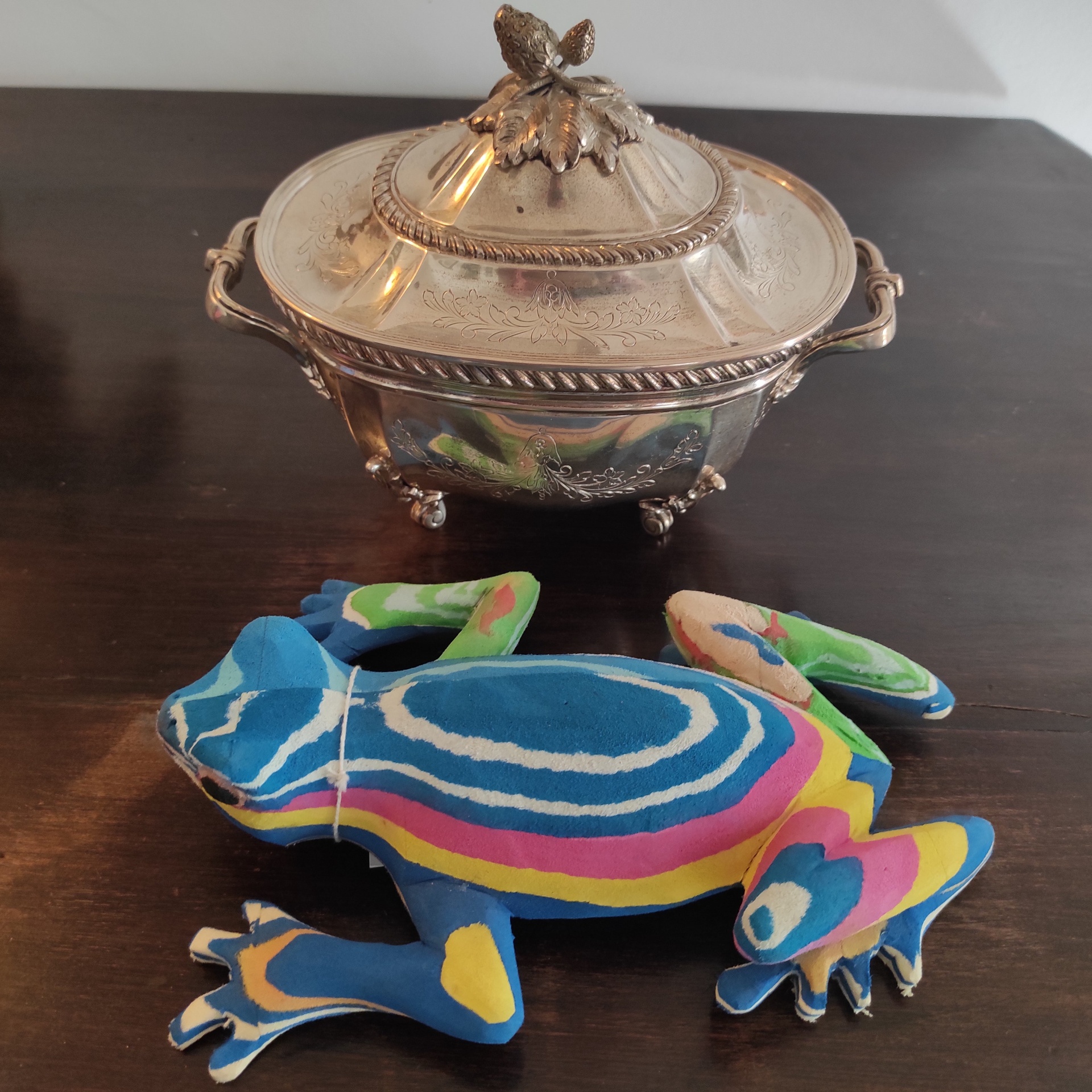 Sapo M Saleiro prateado decorativo e figura colorida de sapo sobre mesa escura