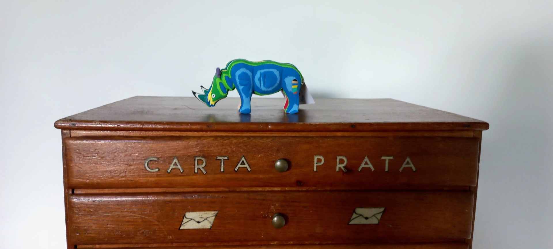 Rimoceronte S Cômoda de madeira castanha com gavetas decoradas e dinossauro de brinquedo azul em cima