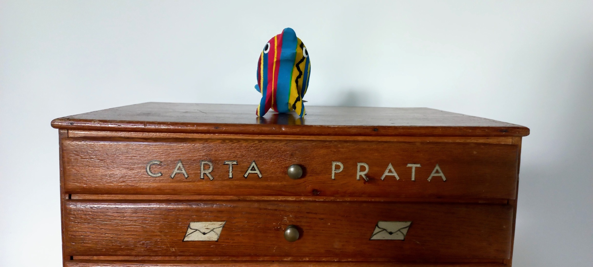 Golfinho S Gaveteiro de madeira castanha com inscrições e figura colorida em tecido no topo