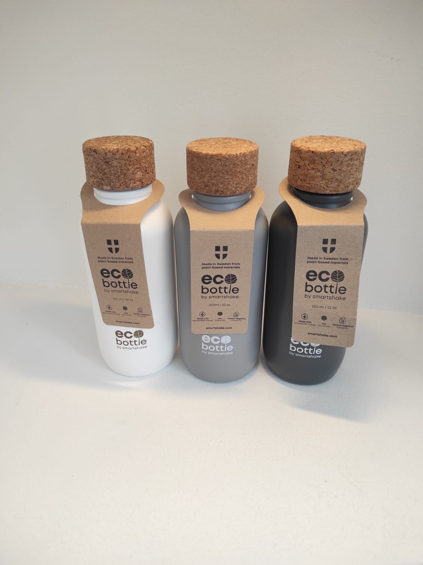 Garrafas EcoBottles 650ml Três garrafas eco bottle de plástico com tampa de cortiça em branco, cinzento e preto