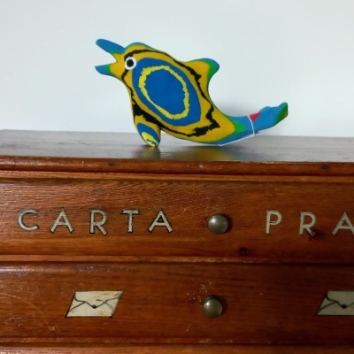 móvel de madeira com gavetas e pássaro decorativo colorido em cima