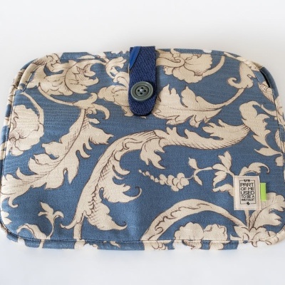 Estojo em tecido azul com padrão floral creme e fecho de botão