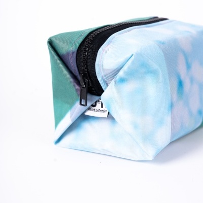 Estojo azul claro e verde com fecho preto e etiqueta visível