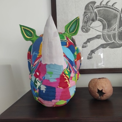 Cabeça decorativa de rinoceronte colorido em tecido com chifre branco e orelhas verdes