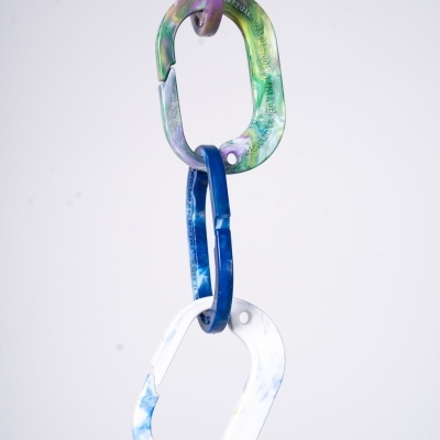 Mosquetões coloridos pendurados em cadeia, fundo claro