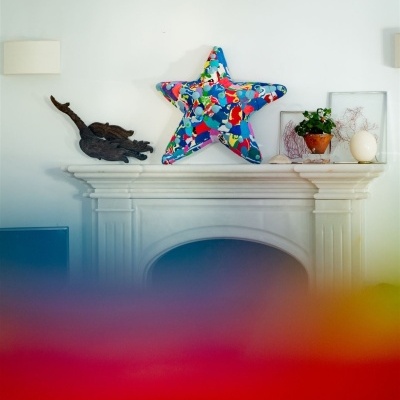 Decoração sobre chaminé branca com estrela colorida e plantas