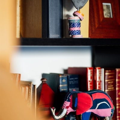 Estante com livros, elefante decorativo em tecido colorido e objeto decorativo em forma de coração cinza