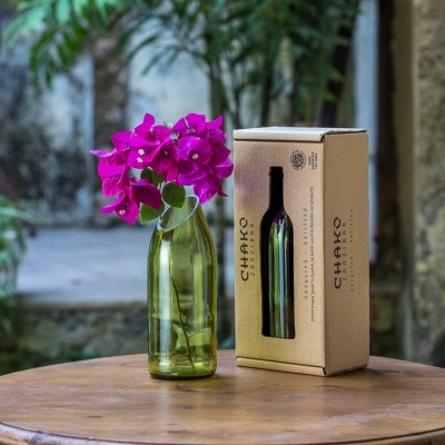 garrafa verde com flores roxas e caixa de cartão CHAKO em mesa redonda de madeira