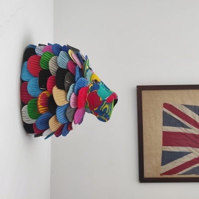 Cabeça de animal decorativa colorida feita de tecido na parede ao lado da bandeira do Reino Unido em quadro