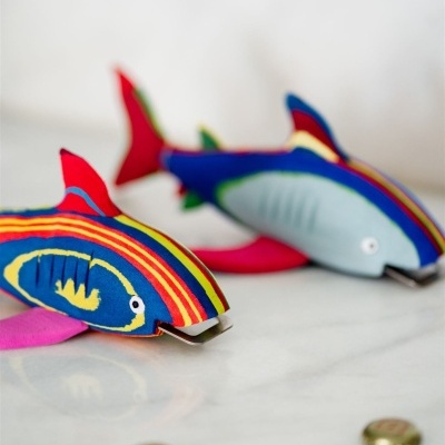 Dois peixes de tecido colorido com padrões listrados em azul, vermelho, amarelo e rosa sobre uma superfície branca