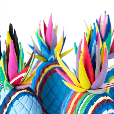 Objetos de tecido coloridos em forma de abacaxi com padrão matelassê e tiras coloridas no topo