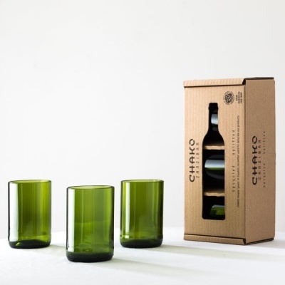Três copos verdes de vidro reciclado e caixa castanha com garrafa