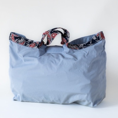 Saco de tecido azul claro com padrão colorido nas bordas e alças