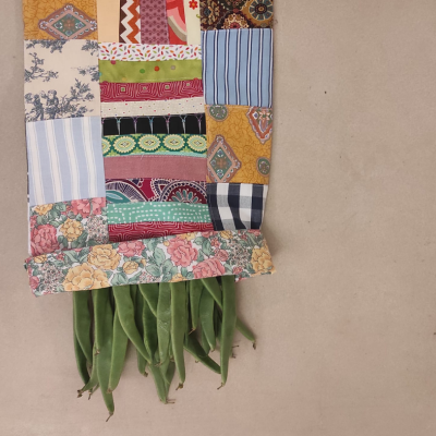 Manta ou saco patchwork colorido com vagens verdes saindo da parte inferior