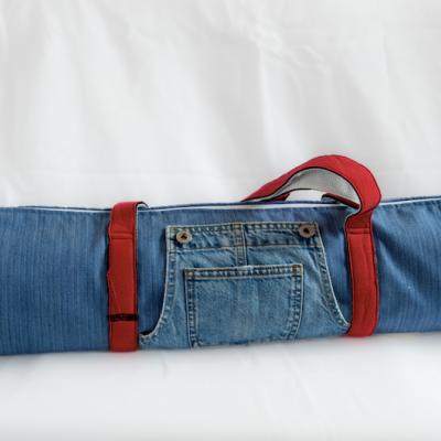 Colchão de yoga enrolado com capa de ganga azul e alças vermelhas